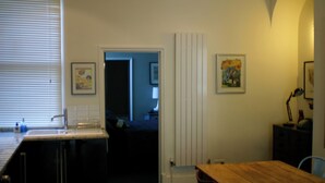A kitchen with a sink, a wooden table, and a door leading to another room. There are framed pictures on the walls. - Breathtaking Flat in Central Bath !! (Bath)