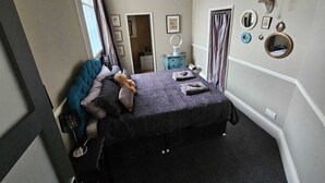 A bedroom with a bed, a dresser, a mirror, and a wall with decorative items. - Breathtaking Flat in Central Bath !! (Bath)