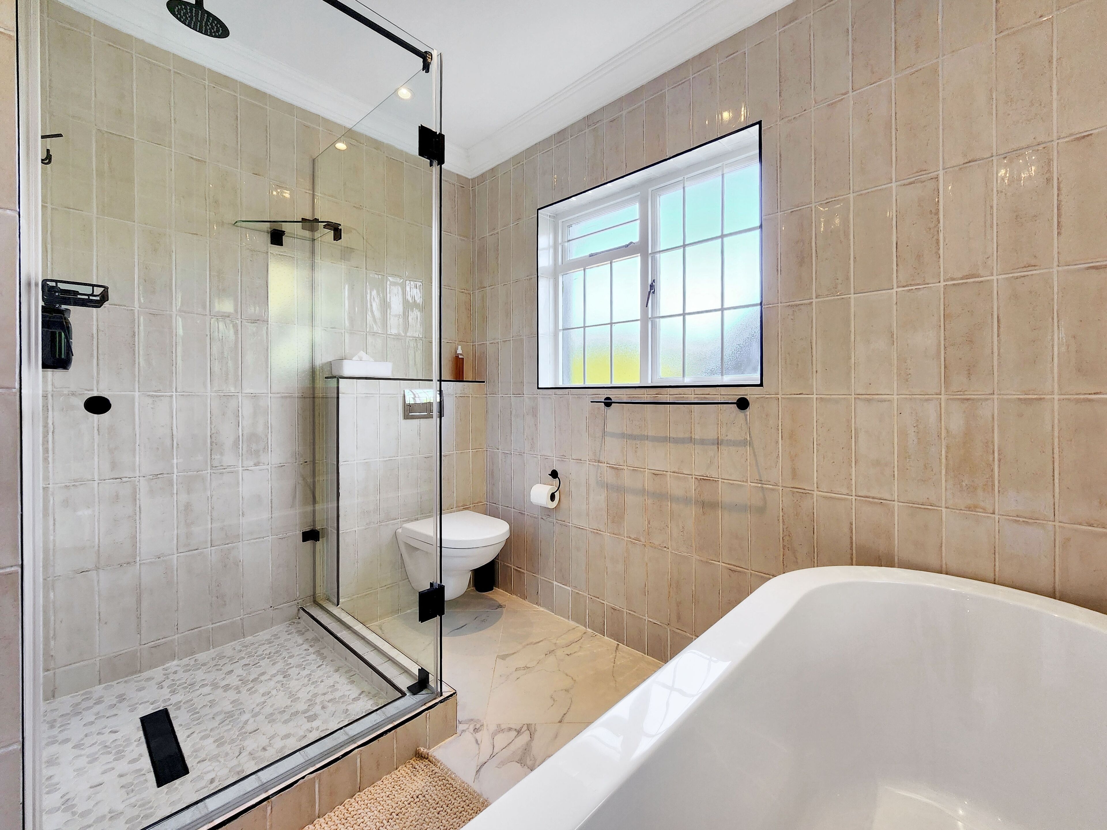 A modern bathroom with a glass-enclosed shower, a toilet, and a bathtub.