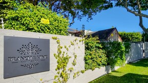A sign for 'Branch & Vine Cottages' with a white wall and greenery. - Eagles Nest - Branch & Vine Cottages (Cape Town)