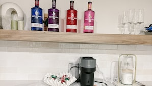 A kitchen with a coffee machine, a jar of sugar, and bottles of gin on the counter. - Cozy Private 1-Bedroom 1 Bathroom Suite  (Calgary)
