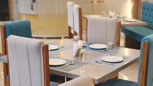 A dining area with tables set for four, each with a placemat, plates, cutlery, and glasses. - Hotel Janas (Tirupati)
