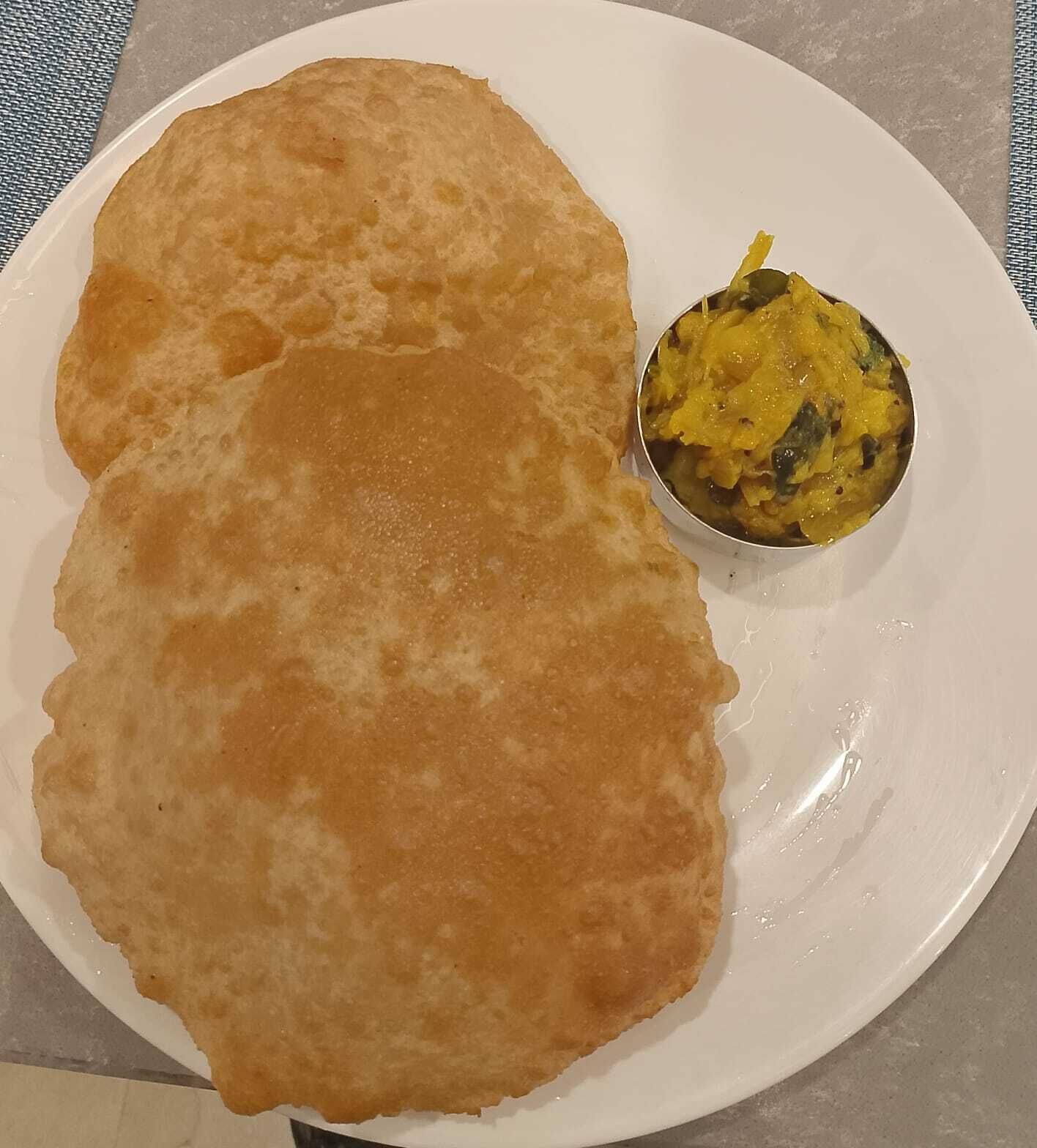Une assiette avec deux pains plats dorés et un petit bol de curry jaune.