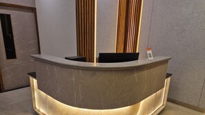 A curved reception desk with a marble finish and integrated lighting. - Hotel Janas (Tirupati)