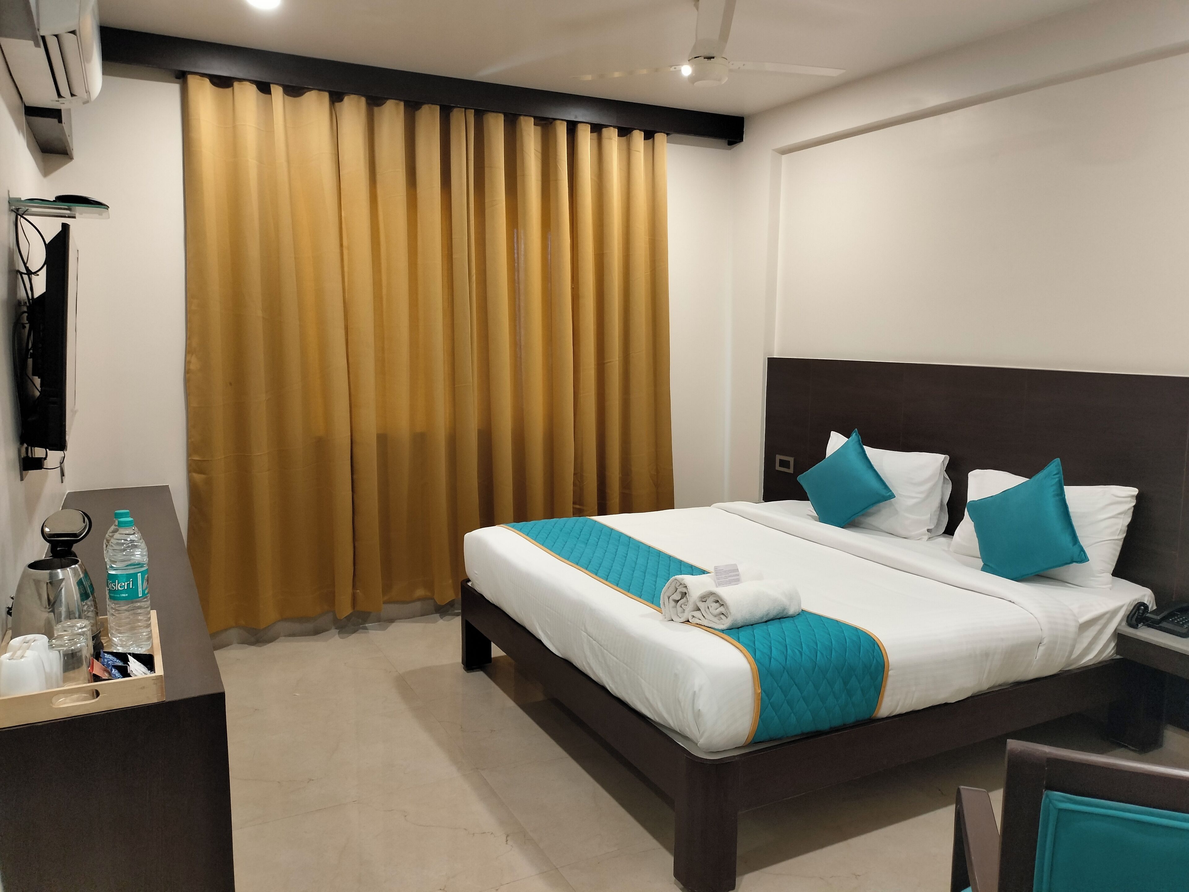 Een hotelkamer met een bed, een bureau, een waterfles en een koffiezetapparaat.