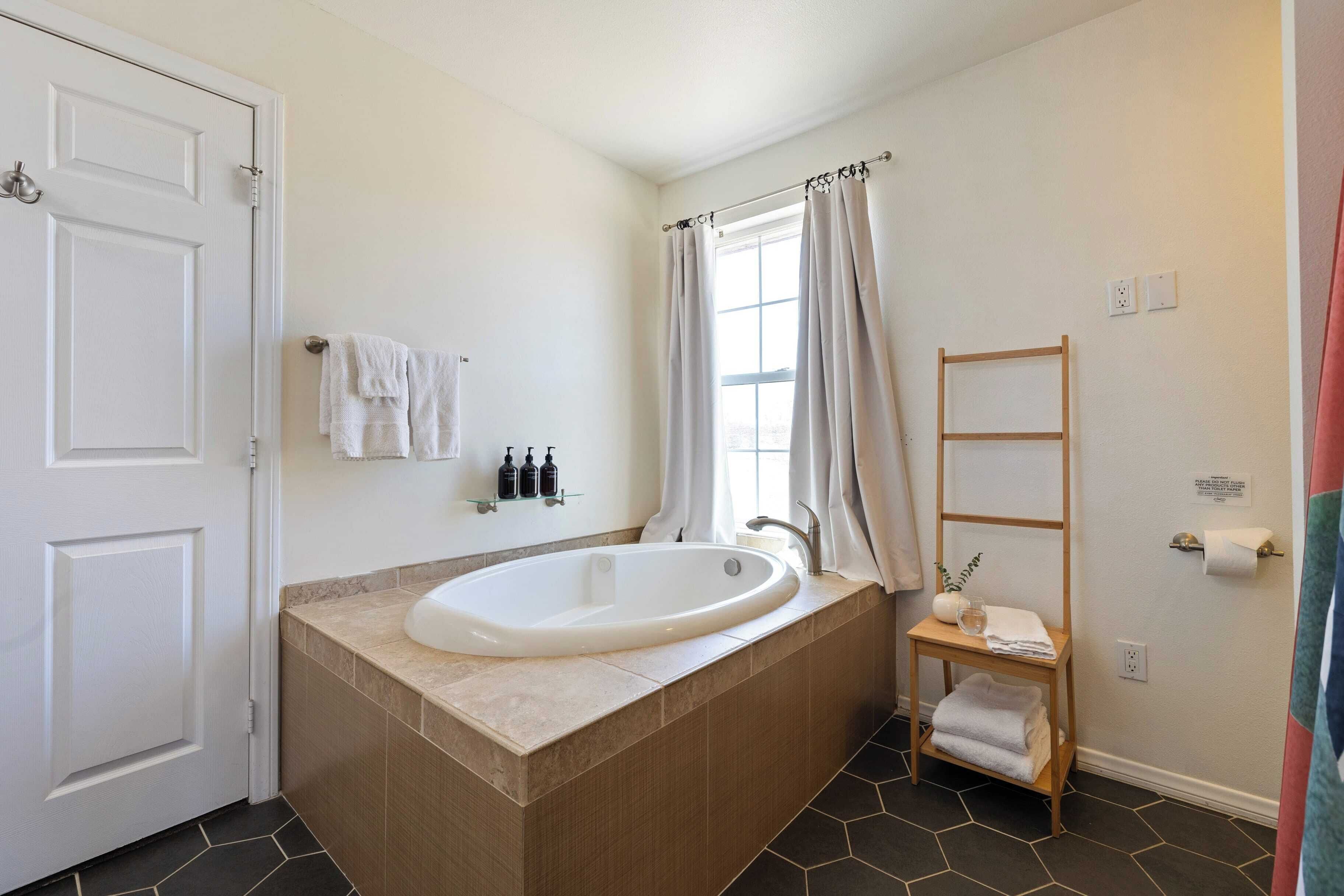Ein Badezimmer mit freistehender Badewanne, einem Holzboden mit Handtüchern und einem Handtuchhalter.
