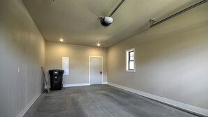 Una habitación amplia y vacía, con suelo de hormigón, paredes color beige y una única ventana.