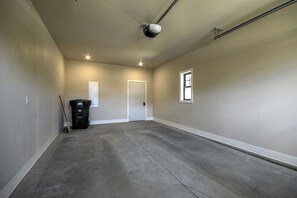 A spacious, empty room with a concrete floor, beige walls, and a single window. - 13 Alpine Basin Loop (Red Lodge)