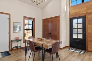 A dining area with a wooden table and chairs, a black door, and a window with a view of the outside. - 13 Alpine Basin Loop (Red Lodge)