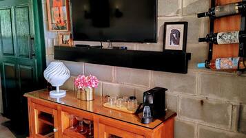 A living room with a TV mounted on a brick wall, a wooden cabinet with glass doors, and a wine rack on the wall.
