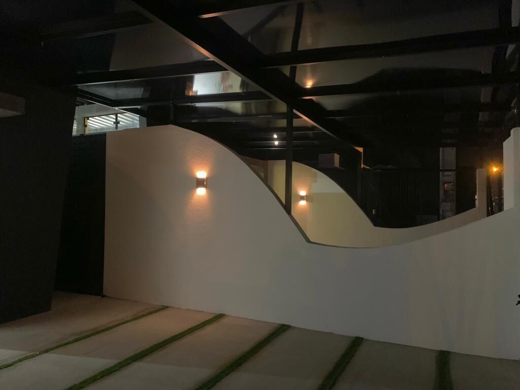 Un interior moderno con una pared blanca curva, una escalera y un techo de cristal.