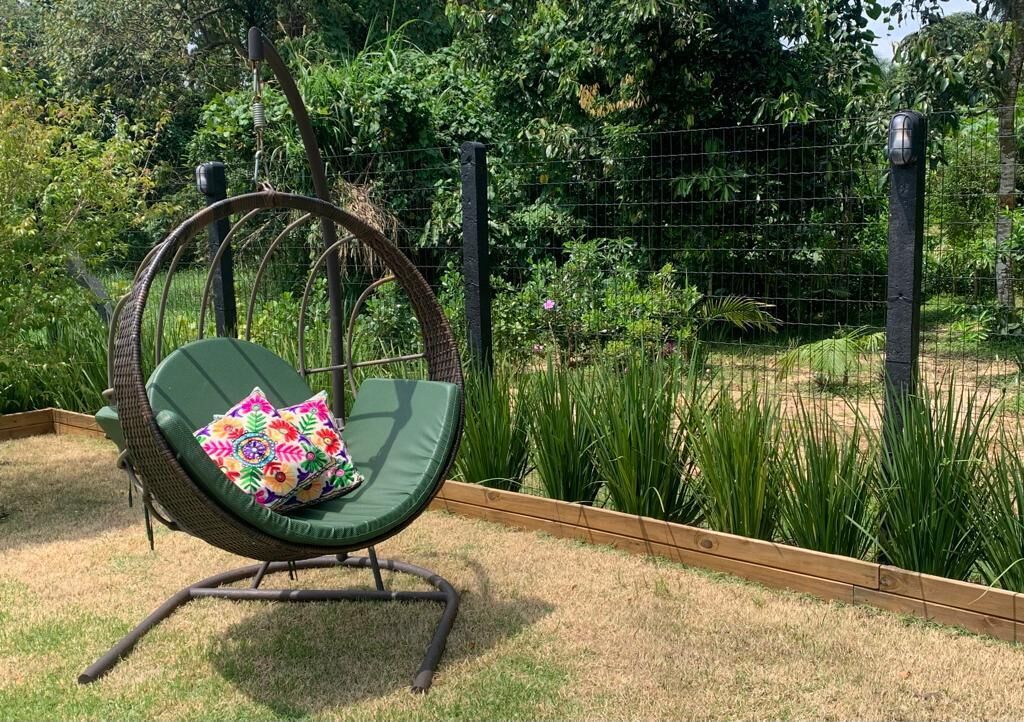Una silla de mimbre con cojín en un jardín.