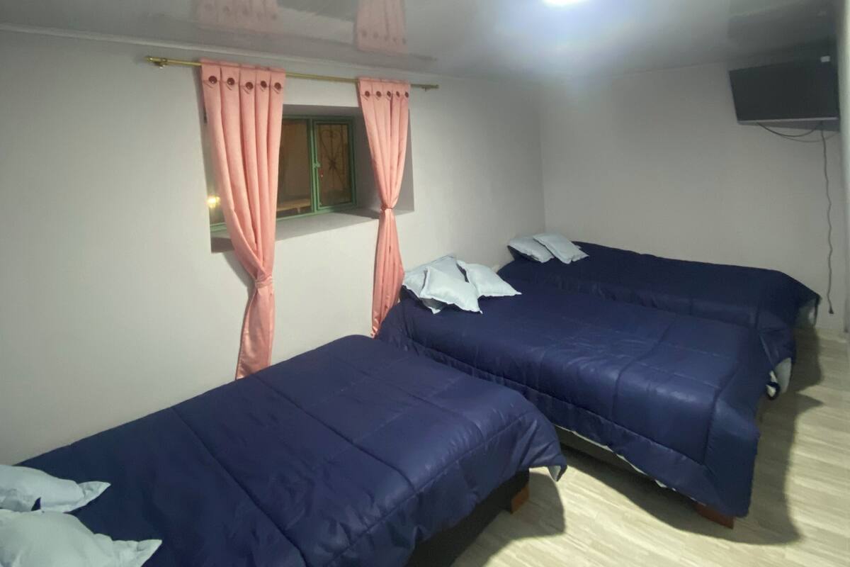 A room with two beds, a ceiling fan, and a TV mounted on the wall.