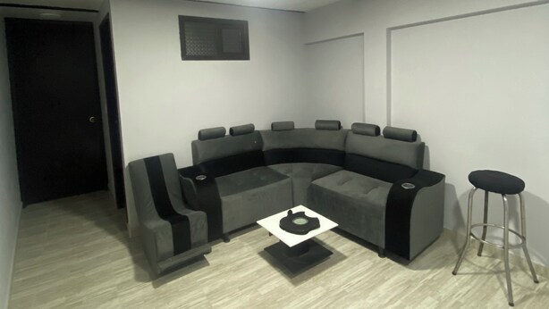 Una sala moderna con un sofá modular, una mesita de centro y un taburete.