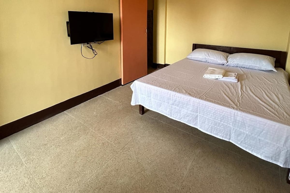 A hotel room with a bed, a television mounted on the wall, and a sliding door.