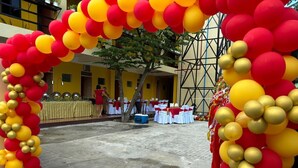 Un espace extérieur en béton agrémenté d’une arche décorative faite de ballons rouges et jaunes.