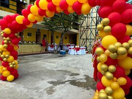 Un espacio exterior de concreto con un arco decorativo hecho de globos rojos y amarillos.