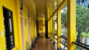 Un couloir aux murs jaunes, agrémenté de rampes noires et de plantes en pot.