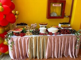 Una mesa de buffet con diversos alimentos y un cartel que dice 'ROMPER EN CASO DE EMERGENCIA' en la parte superior.