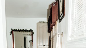 Ein Badezimmer mit Holzboden, einem Spiegel, einem Handtuchhalter und einem Papierkorb.