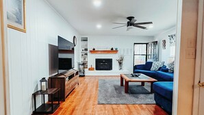 Ein geräumiges Wohnzimmer mit Kamin, blauem Sofa und Holzboden.