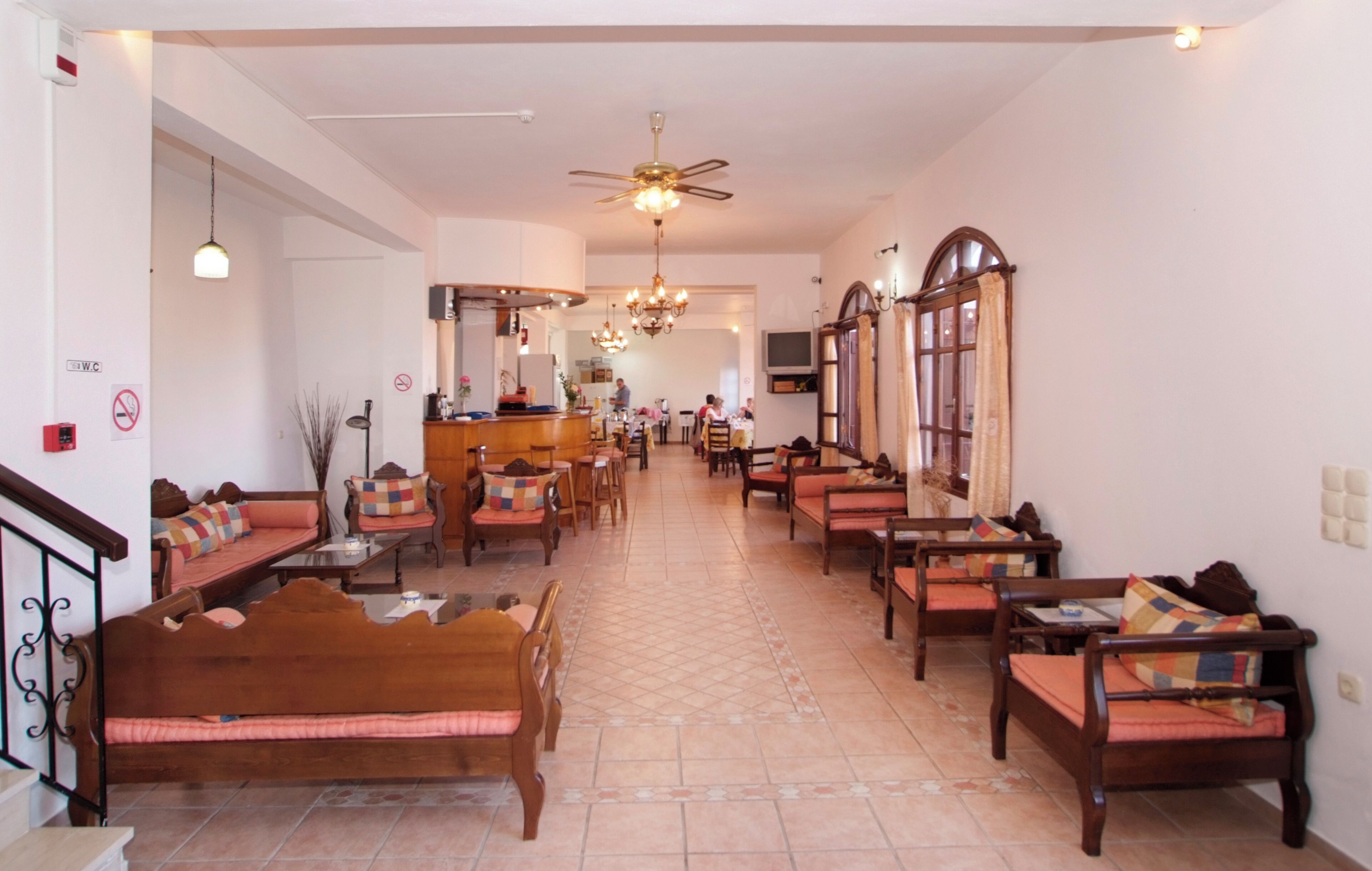 A spacious hotel lobby with a high ceiling, a central chandelier, and multiple seating areas with wooden furniture and colorful cushions.