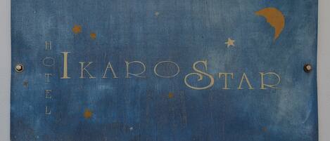 A blue sign with the text "Ikarostar Hotel" and decorative stars and a crescent moon.