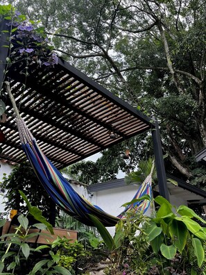 A hammock under a wooden pergola in a garden with various plants and trees. - #2 This traditional architectural house with modern&contemporary finishes (Medellín)