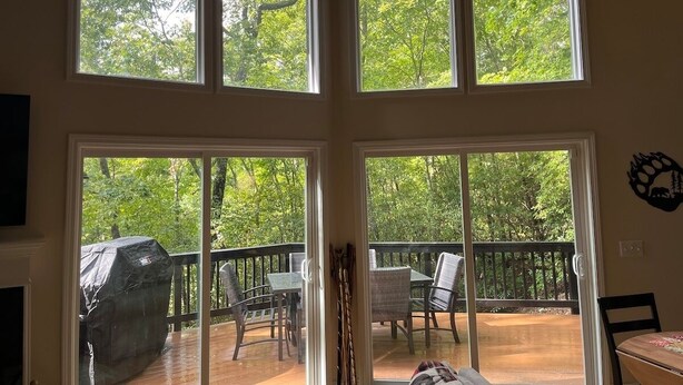 A room with large windows overlooking a deck with outdoor furniture and a barbecue grill. - Helen Haus, Sleeps 10, Fire Pit / Pool Table! Golf (Helen)