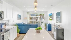 A modern kitchen with white cabinets, a blue sofa, and a central island with a plant.