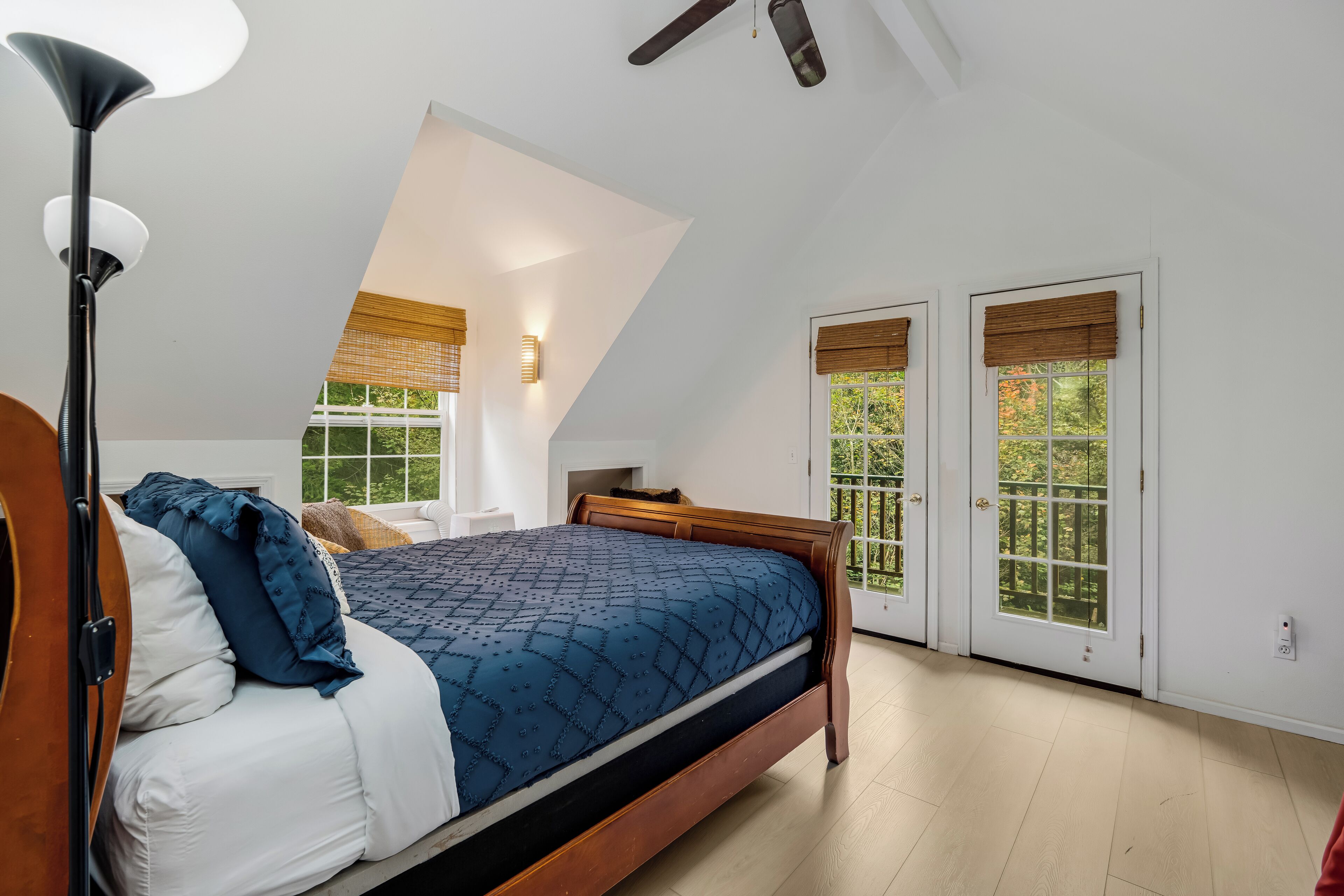 Un dormitorio con cama, lámpara de pie y ventilador de techo.
