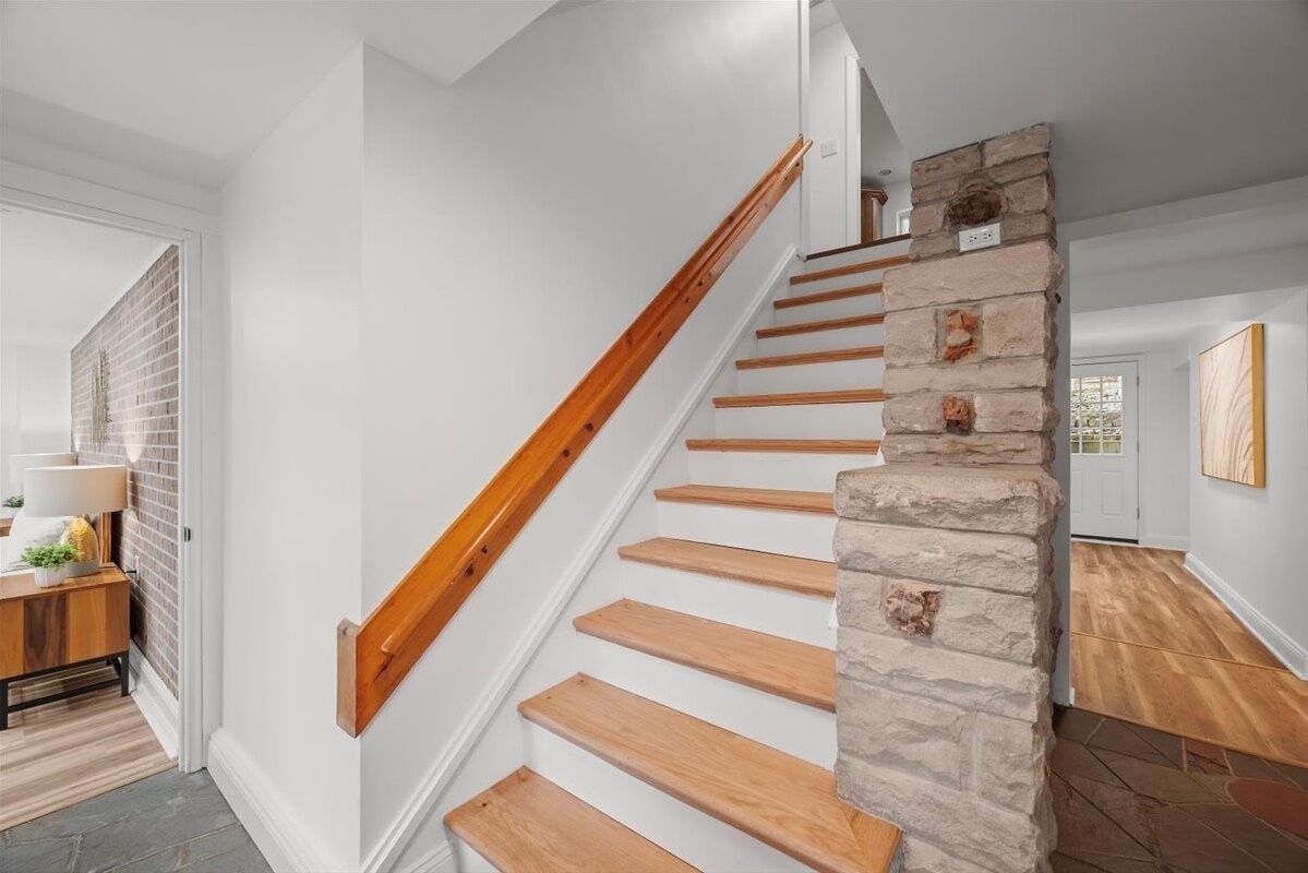 Una escalera con peldaños de madera y un muro decorativo de piedra.
