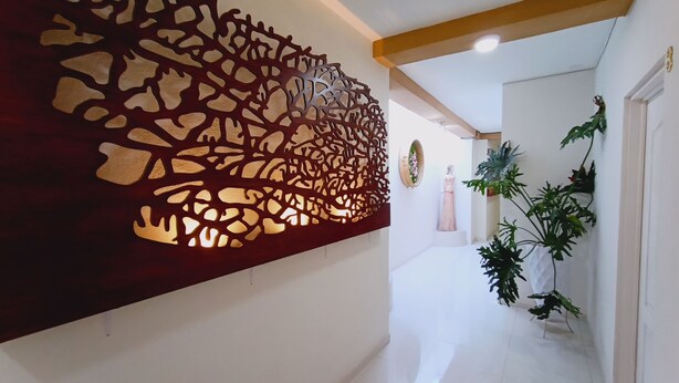 Un pasillo con un panel decorativo en la pared, una estatua y plantas en macetas.