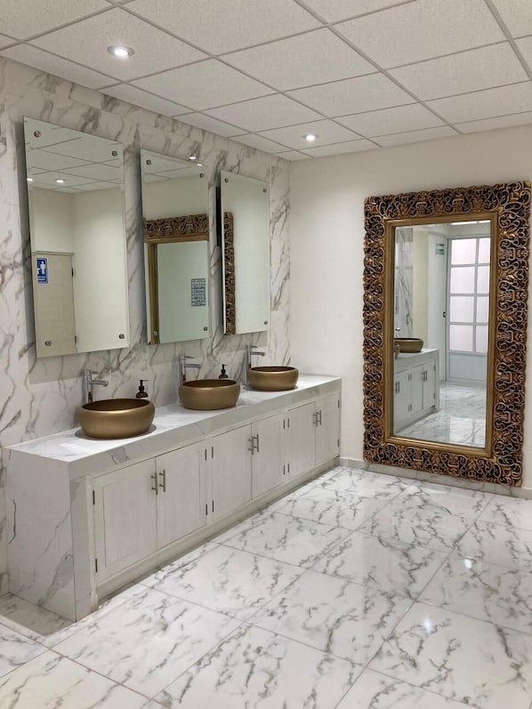 A bathroom with marble flooring, a vanity with three sinks, and a large mirror with an ornate frame. - Hotel Anturio (Dolores Hidalgo)