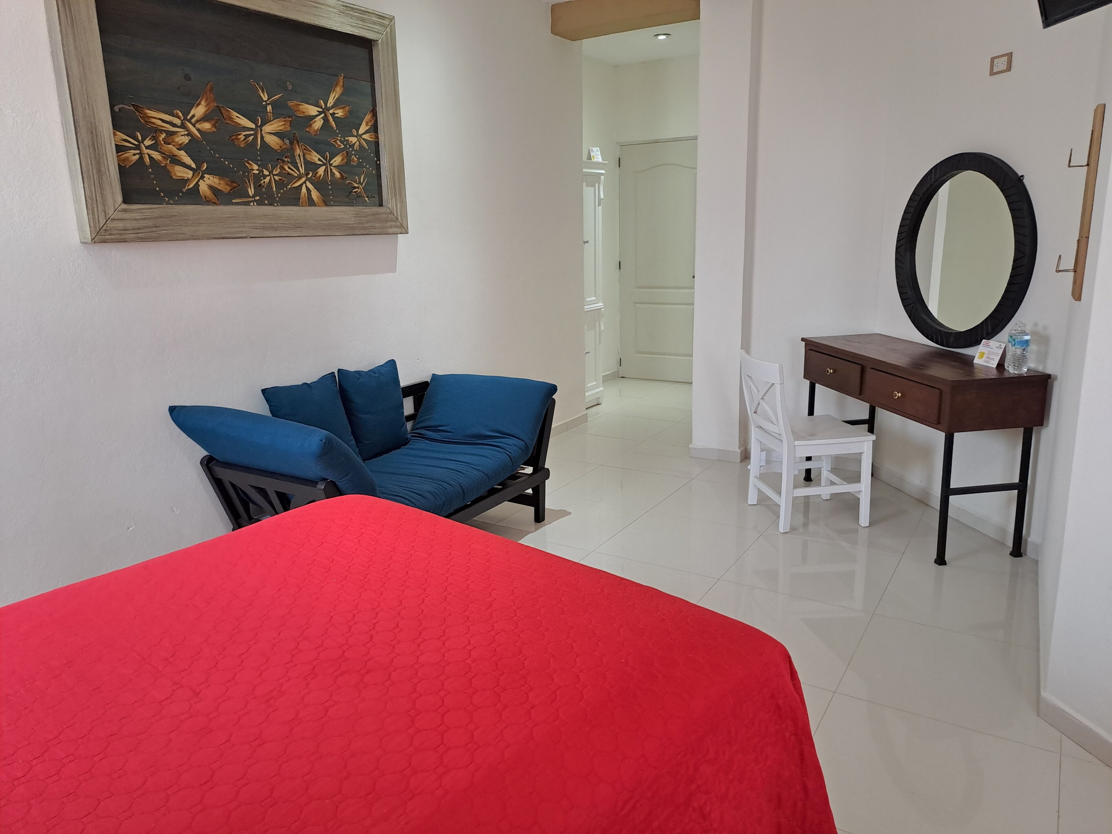 Una habitación con cama, escritorio, silla y un cuadro en la pared.