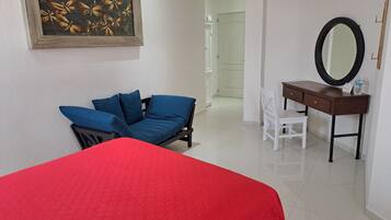 Una habitación con cama, escritorio, silla y un cuadro en la pared.