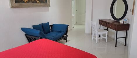 Una habitación con cama, escritorio, silla y un cuadro en la pared.
