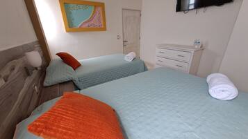 A bedroom with two beds, a TV, a bedside table, and a wall-mounted artwork.