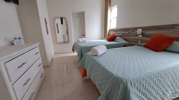 Ein Hotelzimmer mit zwei Betten, einem Schminktisch, einem Spiegel und einem Flachbildfernseher.