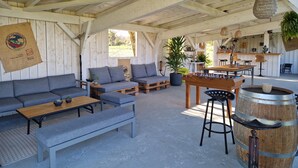 A rustic wooden interior with a sofa, coffee table, and bar stools.