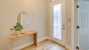 A hallway with a wooden bench, a potted plant, a mirror, and a door with a glass panel. - Townhome w/ Patio < 5 Mi to UF Campus! (Gainesville)
