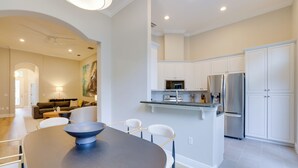 A modern kitchen with white cabinets, a built-in microwave, and a stainless steel refrigerator. There is a dining area with a dark table and white chairs. - Townhome w/ Patio < 5 Mi to UF Campus! (Gainesville)