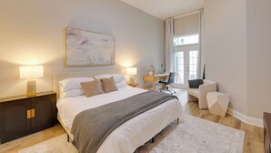 A modern bedroom with a large bed, bedside lamps, a desk, and a chair. - Townhome w/ Patio < 5 Mi to UF Campus! (Gainesville)