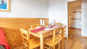 A dining area with a wooden table set for four, surrounded by wooden chairs. - Hermine - apt 6p, vue montagne (Chamrousse)