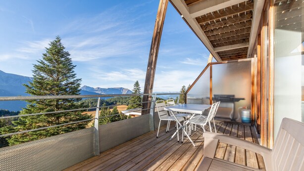 A wooden deck with a table and chairs, overlooking a lake and mountains. - Hermine - apt 6p, vue montagne (Chamrousse)