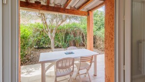 Un patio abierto con una mesa y sillas, techo de madera y vistas al verdor exterior.