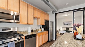 A modern kitchen with stainless steel appliances, wooden cabinets, and a granite countertop.