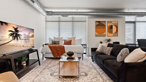 A modern hotel room with a bed, a sofa, a coffee table, and artwork on the walls.