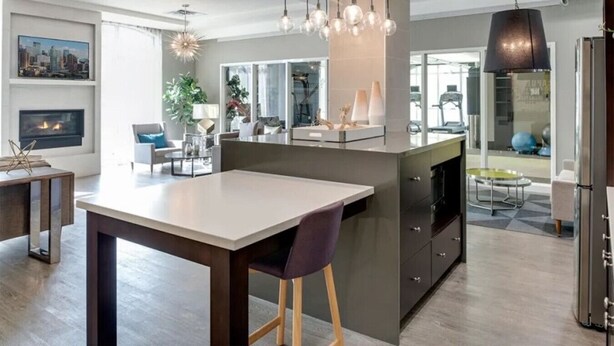 A modern kitchen with a central island, pendant lighting, and a view to the living area.