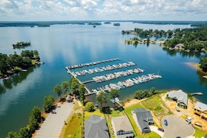 An aerial view of a marina with docked boats, a parking lot, and surrounding greenery.